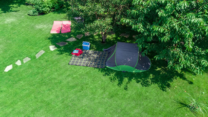 Aerial top view of campsite from above, tent and camping equipment under tree, family vacation in camp outdoors concept 
