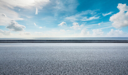 Asphalt road and lake water under blue sky.