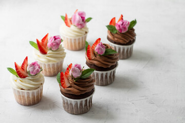 Cupcakes are decorated with strawberries and roses