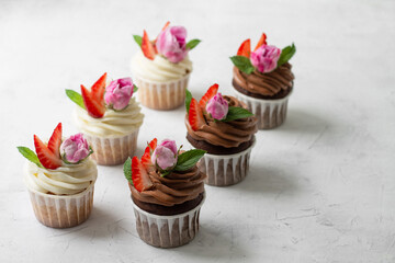 Cupcakes are decorated with strawberries and roses