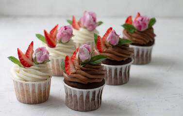 Cupcakes are decorated with strawberries and roses
