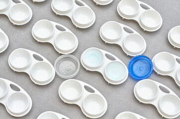 lenses in a container on a gray background. a pattern of containers for lenses