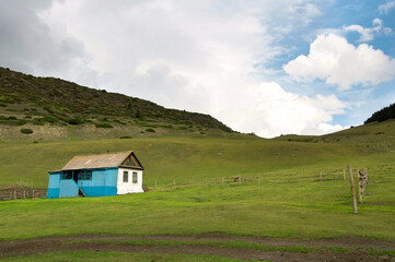 Fototapeta na wymiar Abandoned introvert house with amazing green lawn at the foreground in Kyrgyzstan