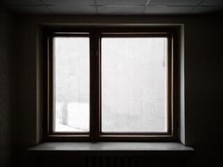 Window overlooking the wall. Silhouette of a window in dark interrior behind which the wall is visible. Textured silhouette of window.