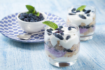 cake-trifle from the berries of honeysuckle, cheesecake,brownies.Two glasses and a plate of honeysuckle berries stand on a blue background