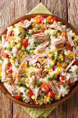 Tasty salad of rice, tuna and seasonal vegetables close-up in a plate. vertical top view