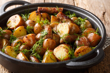 Traditional food fresh fried potatoes with sausages, garlic and dill closeup in a pan. horizontal