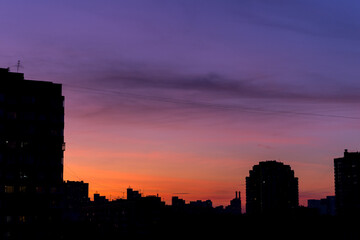 Fototapeta na wymiar Pink orange purple sunset over the city. Multicolored sky and black silhouette tall buildings of the metropolis