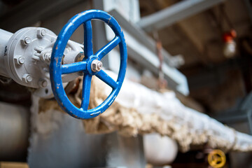 Industrial pipeline flanges blue hand wheel and valve close up, blur industrial pipelines background. Old rusty control equipment, abandoned plant industry with copyspace.