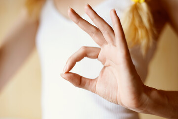 Naklejka premium Female hand shows ok sign on the background of the young body in a white T-shirt