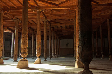 Beautiful wooden columns with elegant carvings and the ray of light shining in ancient mosque