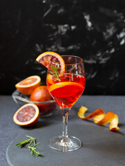 Blood orange cocktail on dark background, fruits and peels
