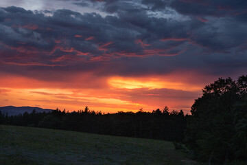 Fototapeta na wymiar Before the rain - sunset over lavender fields - A blaze of orange, red and dark blue tones