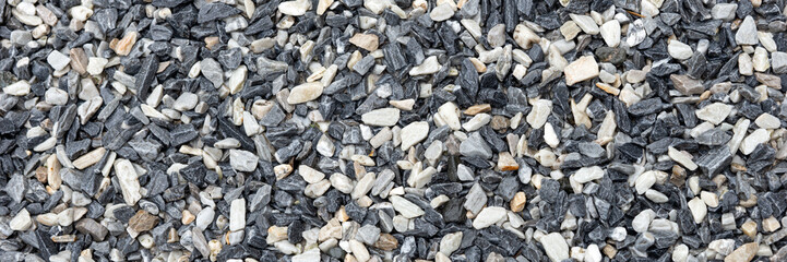 Decorative black and white pebble stones as background. Panoramic picture