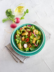 Fattoush salad, Middle Eastern cuisine. Green vegetables, herbs, tomato, radish and pieces of toasted pita bread. Lebanese food. Top view, vertical orientation