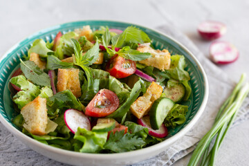 Fattoush salad, Middle Eastern cuisine. Lettuce, herbs, tomato, cucumber, radish and pieces of toasted pita bread. Close up