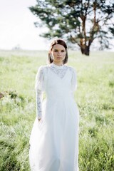 cheerful  woman in long white dress standing  in the field, portrait