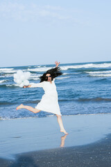 Jumping woman with white balloons on the beach