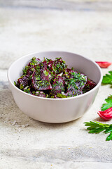 Beetroot salad with garlic and herbs in a gray bowl on white background.