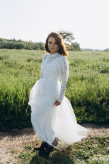 Fototapeta na wymiar beautiful woman in long white dress posing in the field 