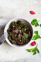 Beetroot salad with garlic and herbs in a gray bowl on white background, top view.