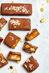 Flat lay of raw vegan chocolate and caramel bars, white background, top view. Healthy desserts concept.