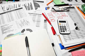 Top view of office employee's desk - work with financial reports, analysis and accounting, tables and graphs, various office items for bookkeeping