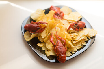 Boiled crayfish and chips on a black plate.