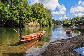 Two Maori waka (traditional canoes) with carved prows on the Waikato River, New Zealand - obrazy, fototapety, plakaty