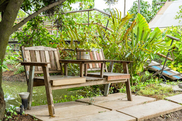 Obraz premium Two wooden chairs under the shade of the garden Near the wooden bridge, looks shady, giving a comfortable 