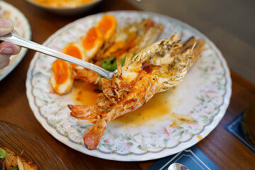 A plate of grilled prawns and fried boiled egg served with sweet and sour tamarind sauce, topped with fried chili and shallot, Traditional thai food.