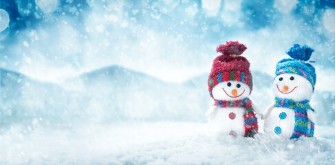 Two happy snowman hold hands in winter scenery with copy space. Christmas background