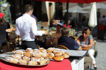  Pastry in focus on a tray near restaurant  on the street, people are blurred