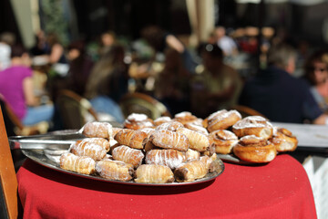  Pastry in focus on a tray near restaurant  on the street, people are blurred