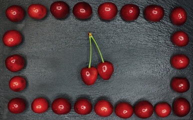 a frame of cherries on a black background and a sprig of cherries inside