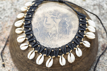 Macrame boho necklace with white shells on vintage metal background