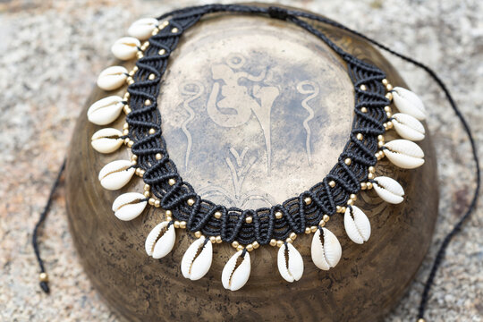 Macrame boho necklace with white shells on vintage metal background