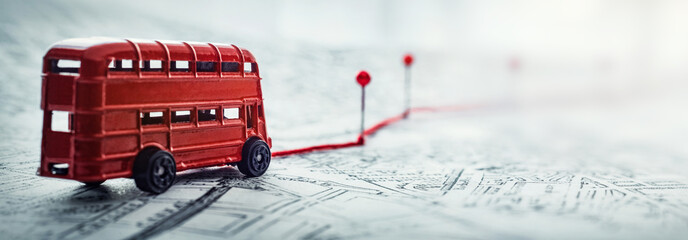 Red bus, pins and route laid on a map of the city. Concept on the  adventure, discovery, navigation, communication, logistics, geography, transport and travel topics.
