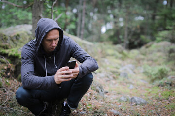 Adult man lost while hiking  in the forest and using phone for helping 
