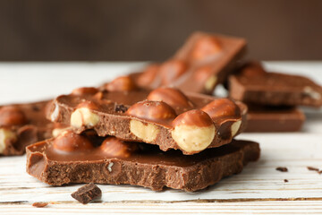 Tasty chocolate pieces on white wooden table