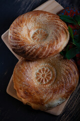 Uzbek tandyr flatbread. Traditional bread in Central Asia - tandyr flatbreadon a black wooden table background, top view.