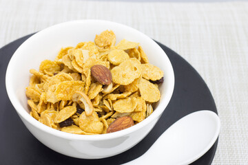 Cornflakes in a white cup placed on a black plate for breakfast