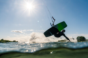 Kitesurfer jumping and sliding with his hand in the water photographed half underwater