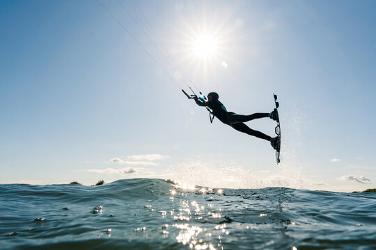 Silhouette of Kitesurfer jumping during daytime with beautiful sun star photographed from the water