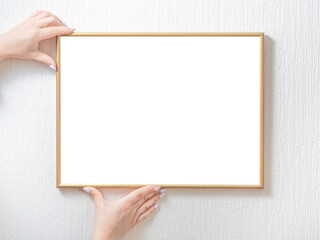 Obraz premium Woman hands holding white empty photo frame hanging on wall