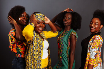 Fototapeta na wymiar Four young beautiful African fashion models have fun and laughing in traditional dress. Women from the Congo Republic, Ivory Coast, and Zimbabwe