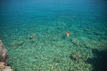 Two women are swimming in the clear sea water, shot from above. Vacation vacation floating and relaxing in nature