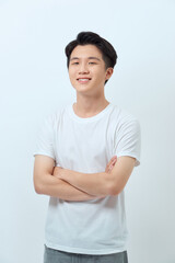 Waist-up portrait of confident Asian man standing against white wall with arms crossed