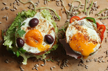 A sandwich with egg, lettuce, tomato, olives and seeds