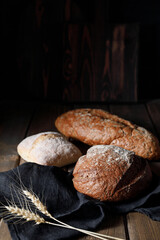 Variety of loaves of bread and buns on wooden table background.